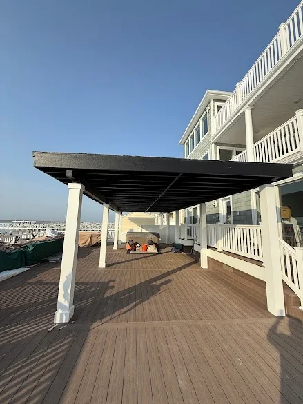 Large deck pergola with white posts and dark beams painted by Andy's Painting LLC