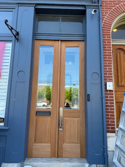 Navy storefront trim and pilasters around wood doors painted by Andy's Painting LLC
